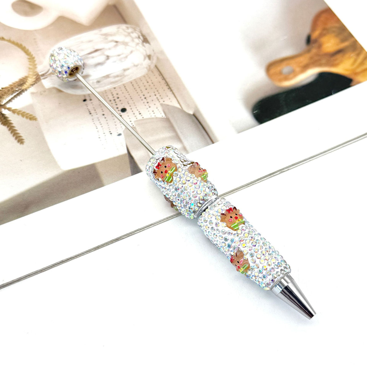 Rhinestone ballpoint pen with colorful cartoon frog charms on a white surface.