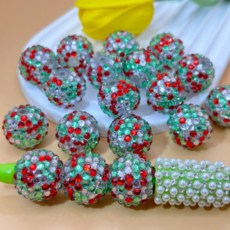 Red, green and clear rhinestone beads on white dish with pearl-decorated green pen