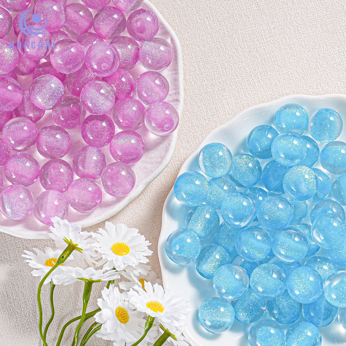 Pink and light blue translucent round gel beads on two white plates with daisies