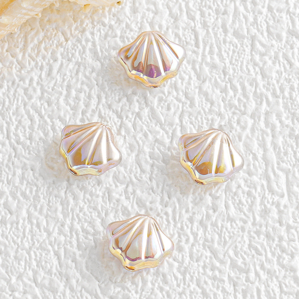 Four iridescent shell-shaped beads with gold-toned edges on a textured white surface