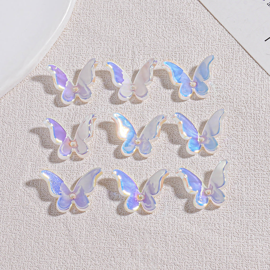 Nine iridescent butterfly acrylic beads in 3x3 grid on textured beige surface