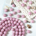 Pink marbled round glass beads with drilled holes scattered on a white surface