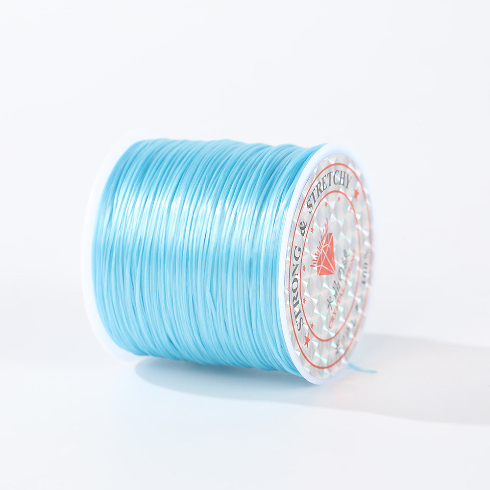 Spool of light blue 0.8mm flat elastic beading cord on its side, white diamond label, white background