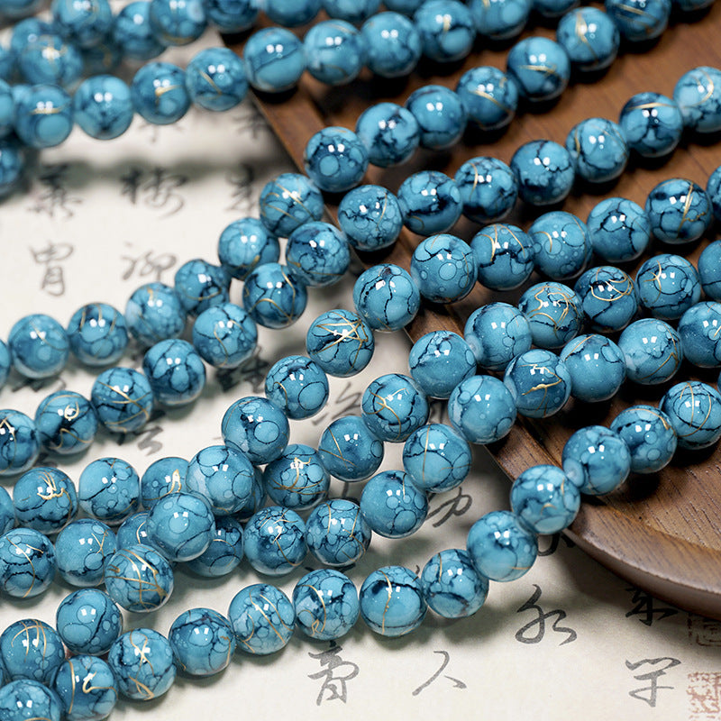 Blue marbled porcelain bead strands with gold leaf accents on a light surface
