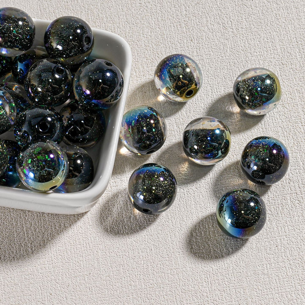 Clear candy-core opal-effect resin round beads filled with black glitter and iridescent flecks in white dish