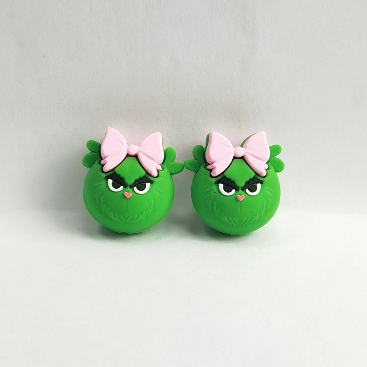 Pair of green Grinch-like silicone focal beads with angry eyes and pink bows