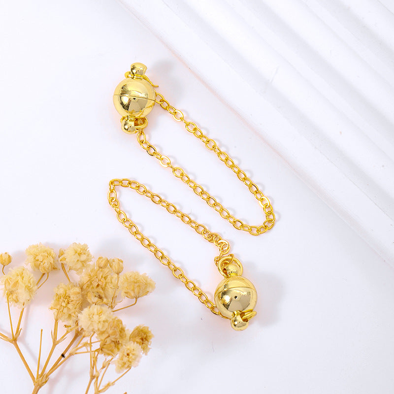 Gold magnetic ball clasp with a safety chain on a white background with dried flowers