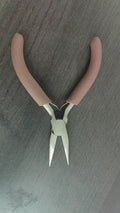 Brown-handled needle-nose jewelry pliers with silver jaws on gray surface
