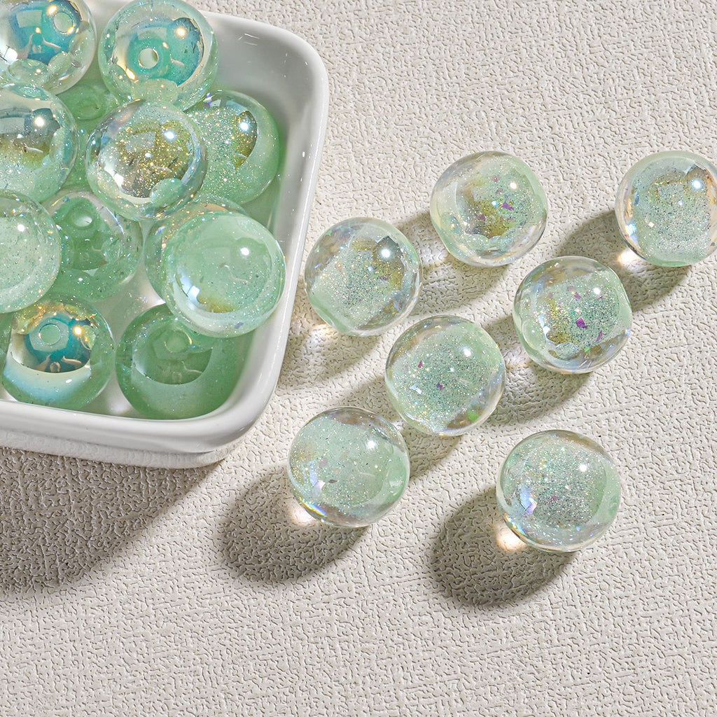 Clear round candy-core opal-effect resin beads with iridescent glitter in small white dish