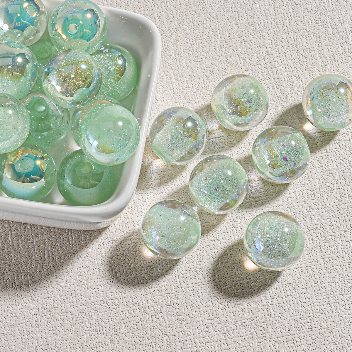 Clear round candy-core opal-effect resin beads with iridescent glitter in small white dish
