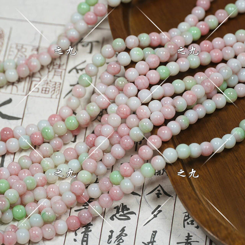 Multicolor round porcelain beads in pink, green, white on wooden tray