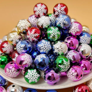 Metallic snowflake printed acrylic round beads in assorted colors piled on a white plate