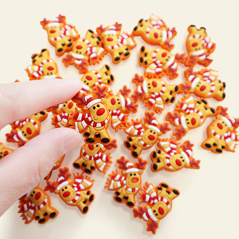 Fingers holding an orange reindeer charm with a red-and-white striped scarf, surrounded by similar charms.