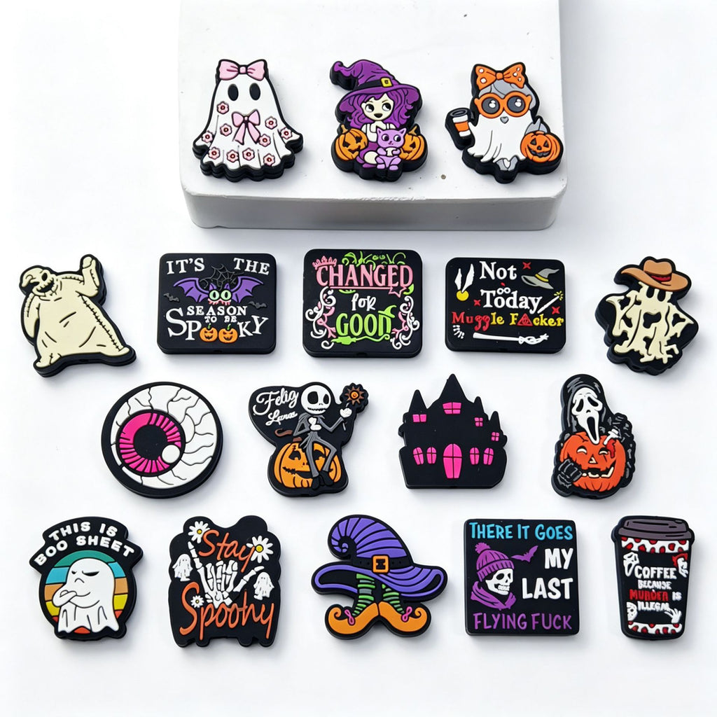 Fifteen Halloween silicone focal beads with ghost, witch, skeleton, pumpkin, and haunted house designs on white.