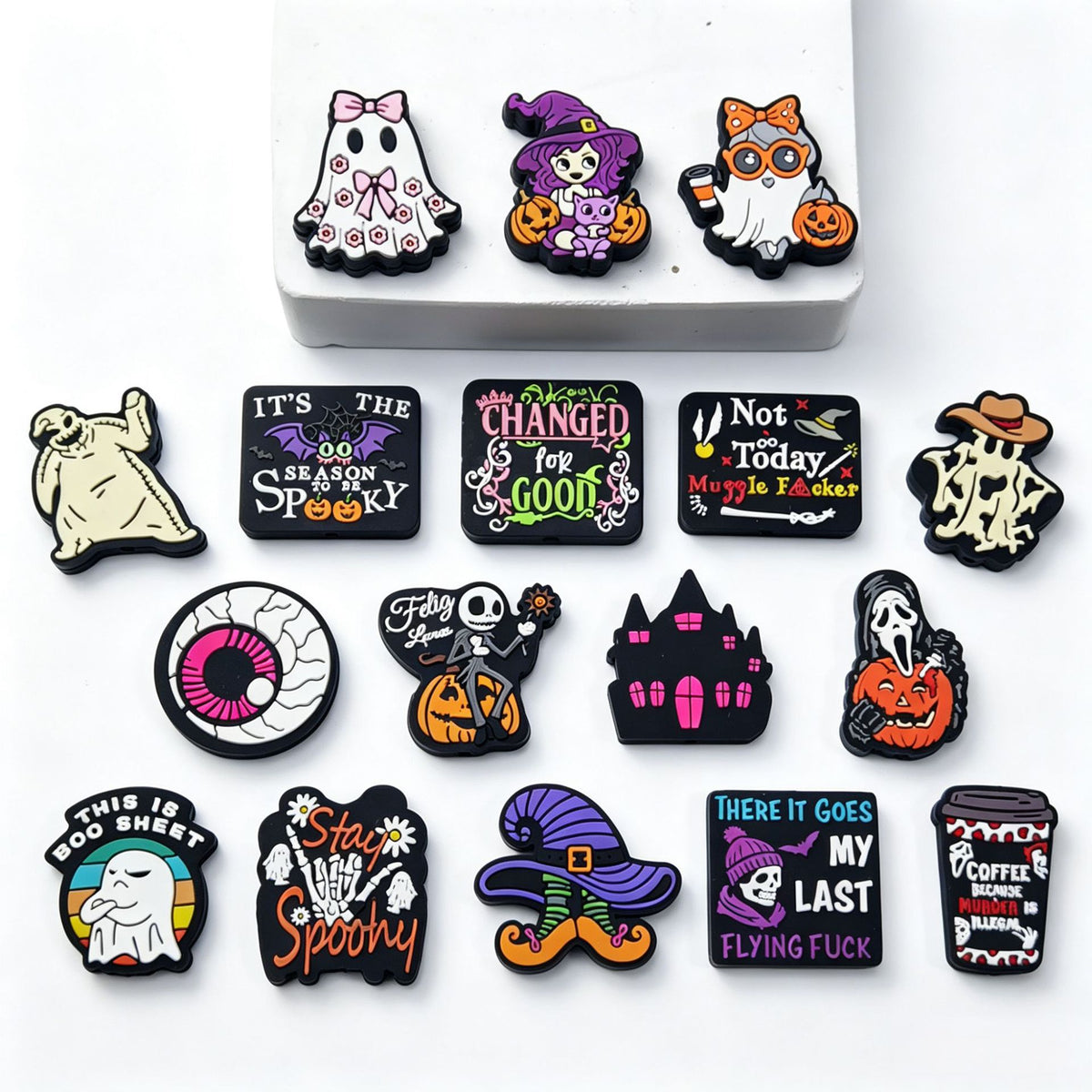 Fifteen Halloween silicone focal beads with ghost, witch, skeleton, pumpkin, and haunted house designs on white.