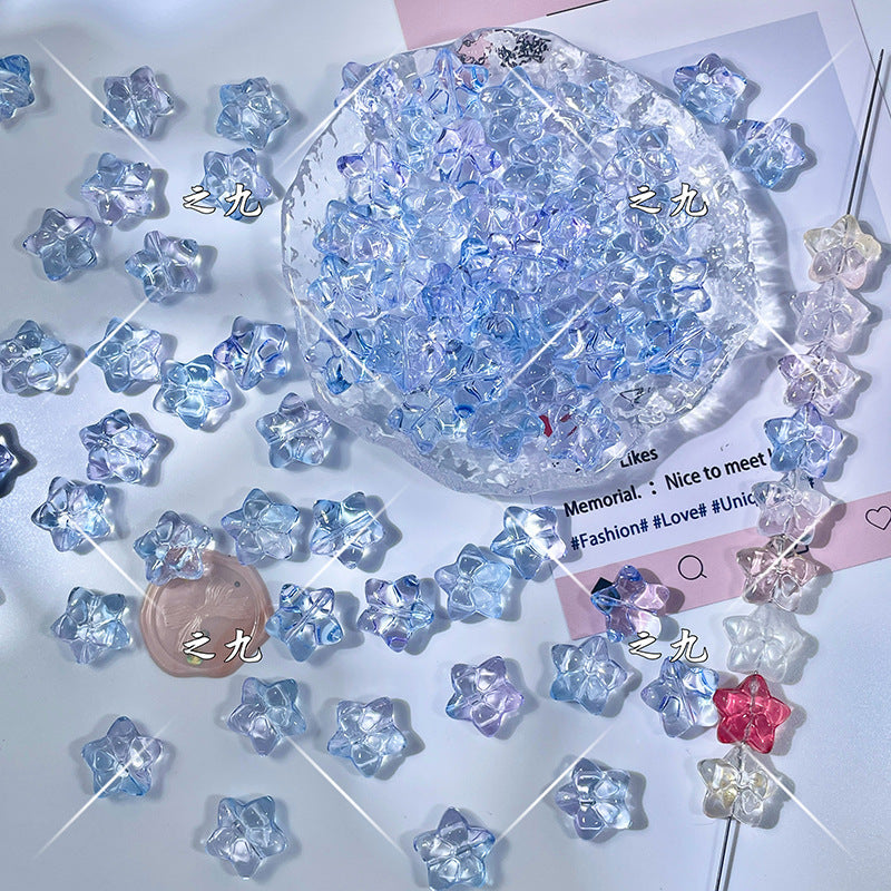 Iridescent star-shaped glass beads in light blue, lavender, and pink on a white surface