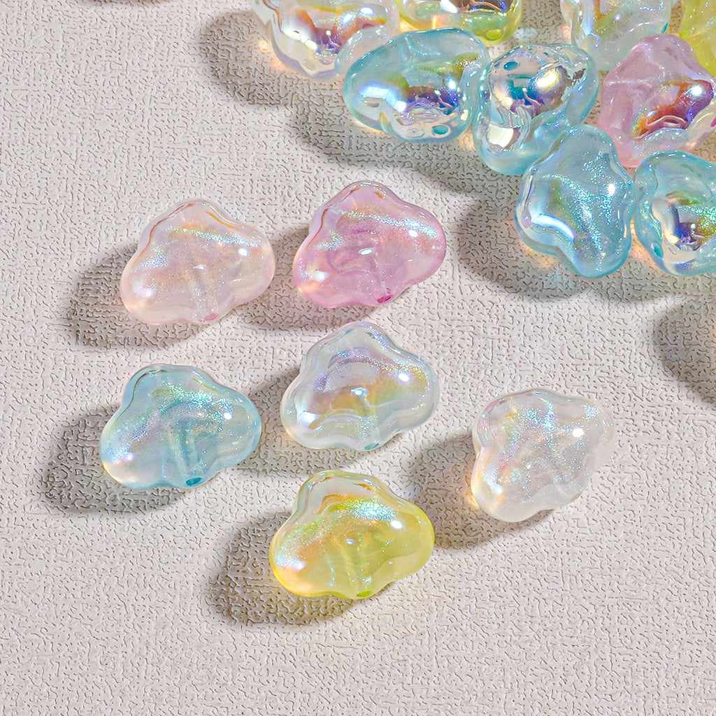 Cloud-shaped iridescent resin beads in pastel colors scattered on beige fabric