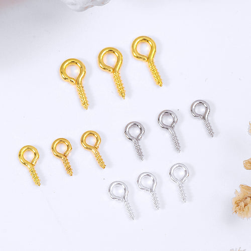 Nine small screw eye pins in gold and silver finishes on a white background