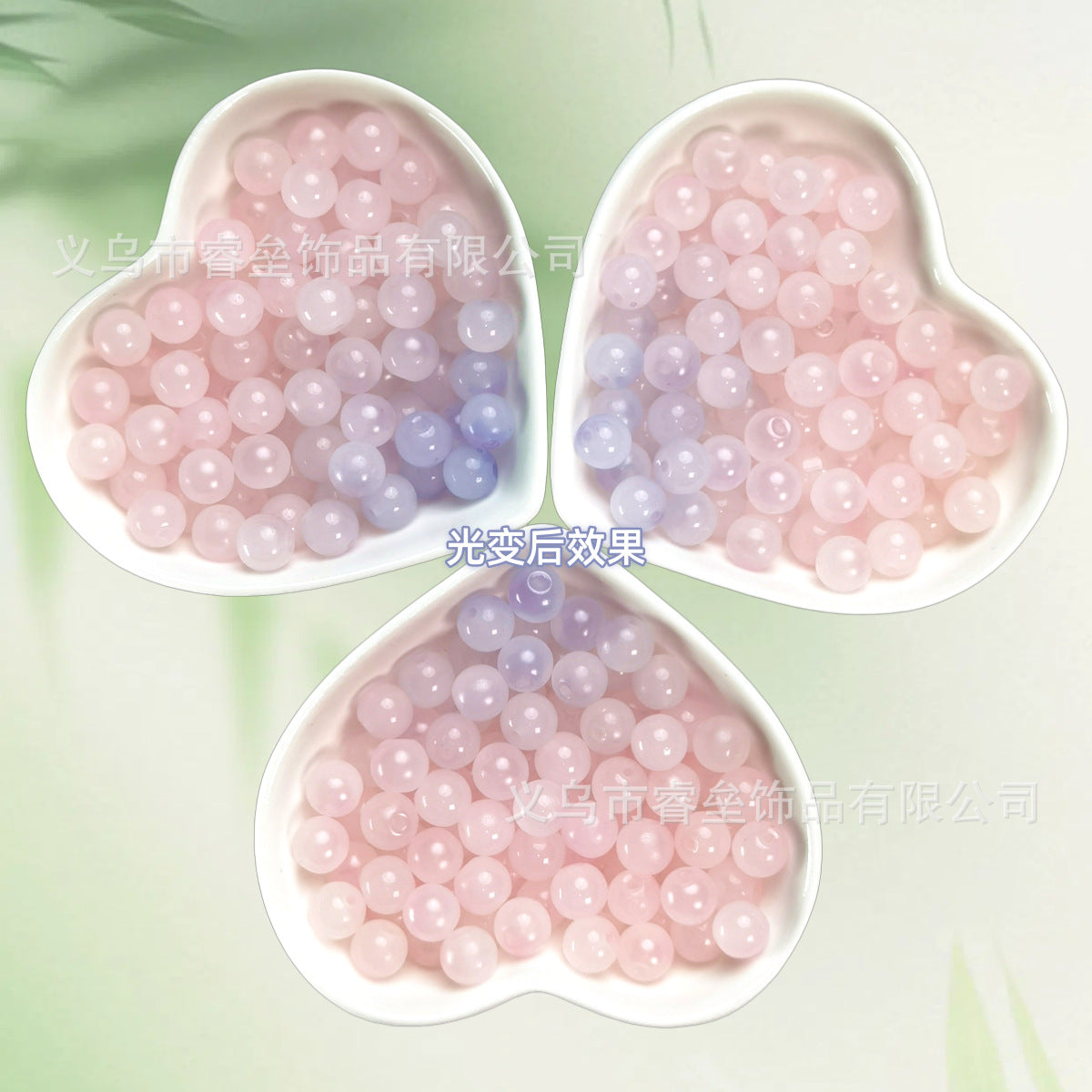 Three heart-shaped dishes of glossy pink and lavender beads on pale green