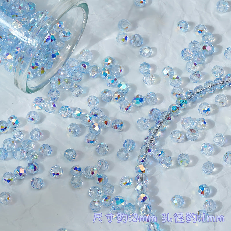 Clear round faceted beads with an iridescent light blue finish scattered on a white surface, with a glass jar tipped over at the top left and a strand of beads laid diagonally across the frame.