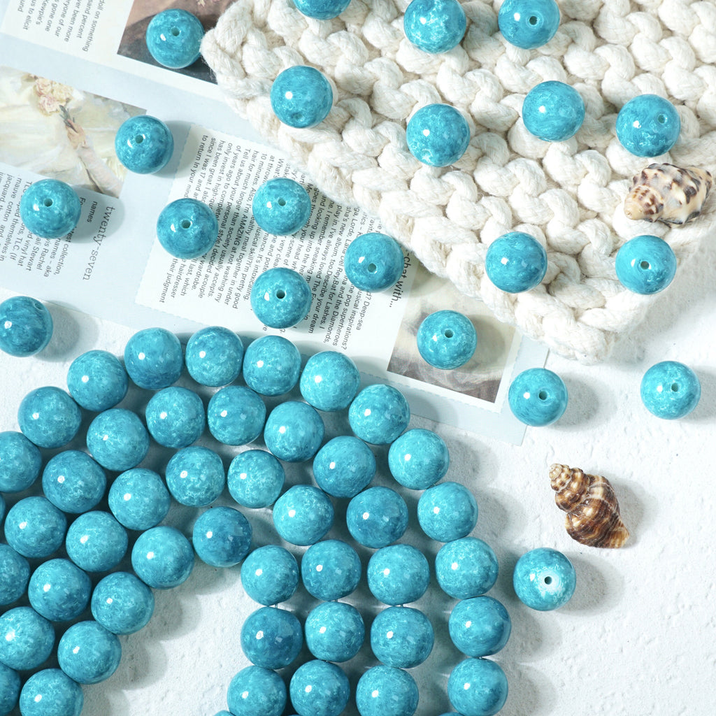 Turquoise-blue marbled round glass beads scattered and on a beaded cord