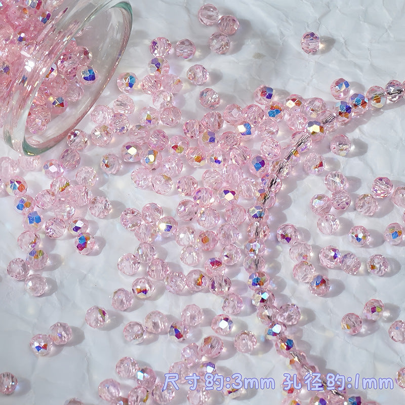 Pink faceted glass beads scattered on a white textured surface, with a glass jar tipped over at the top left. The beads are clear with a pink tint and some show iridescent rainbow reflections.