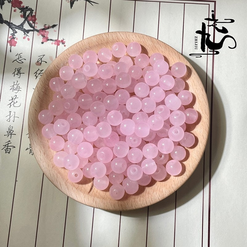Pink translucent round beads in a wooden bowl on white background with Chinese text
