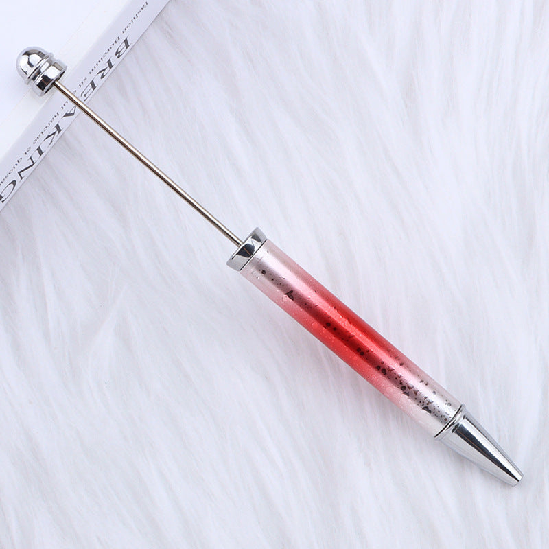 Beadable pen with red gradient barrel and silver accents on a white fabric background.
