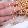 Close-up of fingers holding two rose gold heart-bead chains with spool of chain
