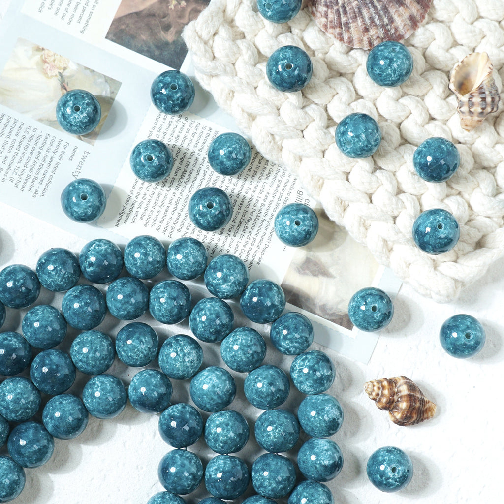 Blue marbled round glass beads scattered on a white surface with a knit blanket
