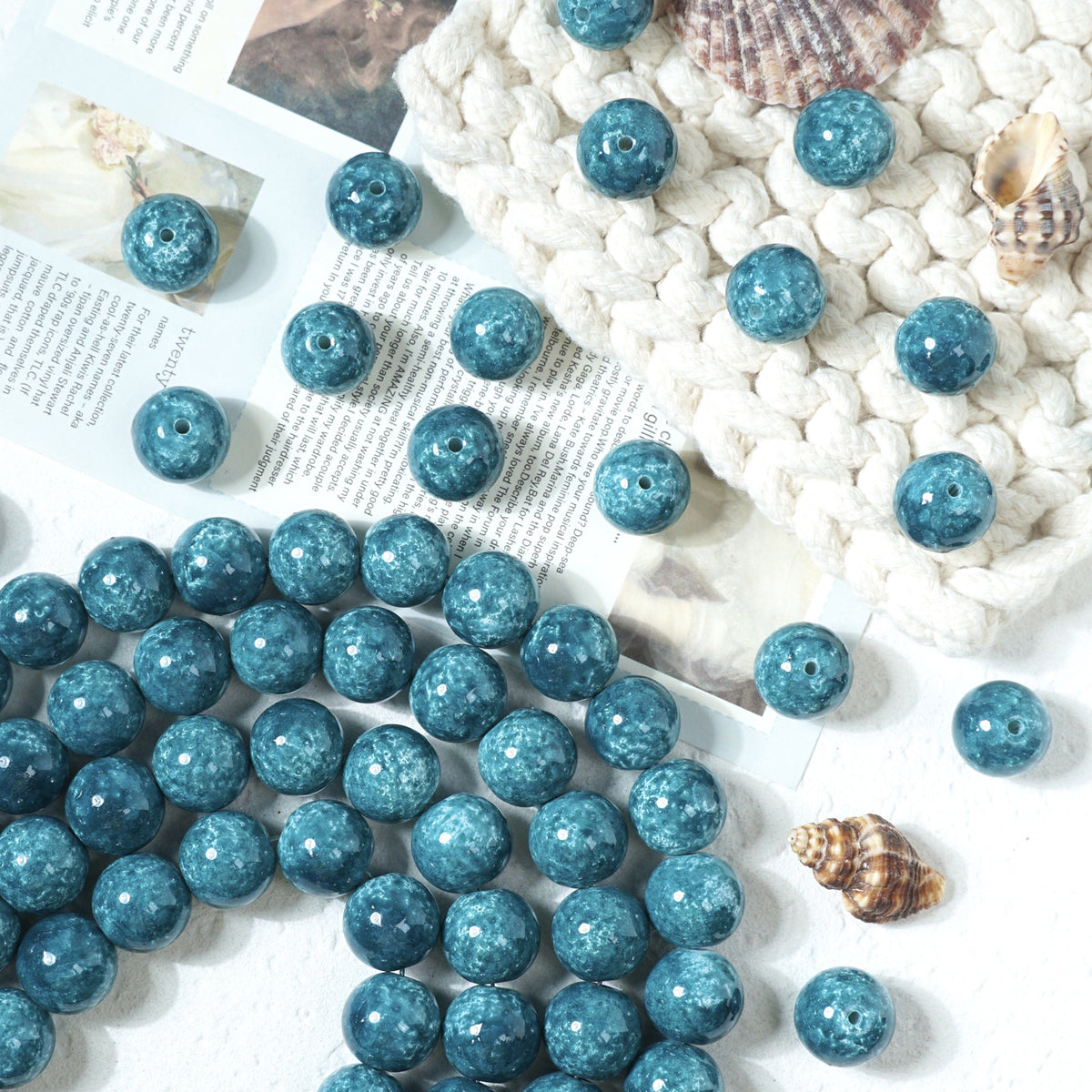 Blue marbled round glass beads scattered on a white surface with a knit blanket