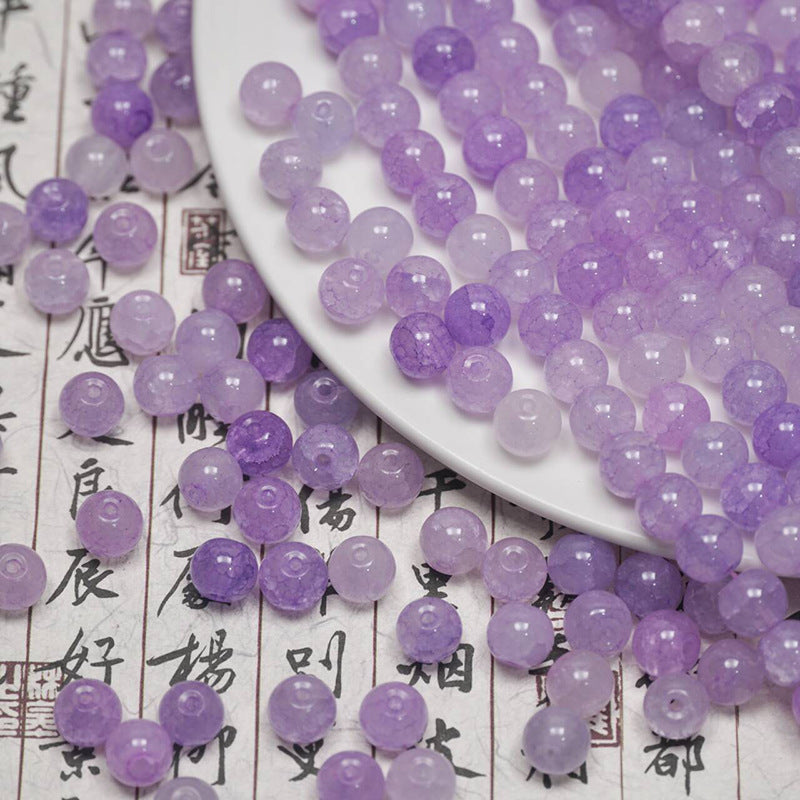 Purple ice-crackle glass beads spilling from a white plate onto calligraphy paper