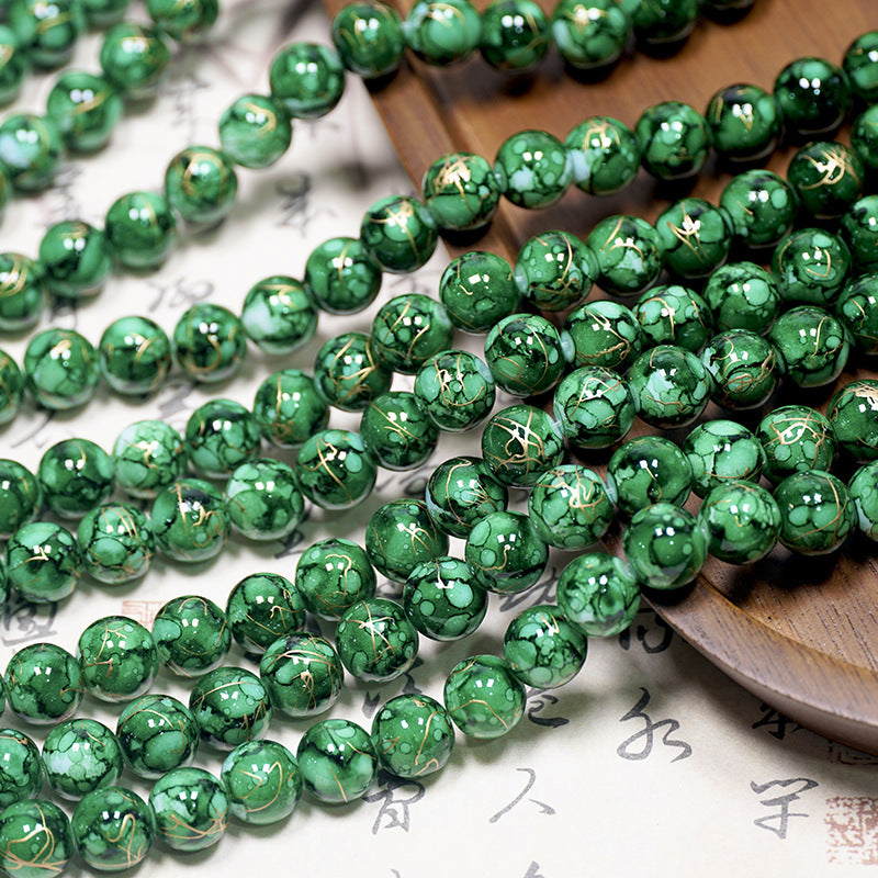 Green marbled porcelain bead strands with gold foil accents on a light surface