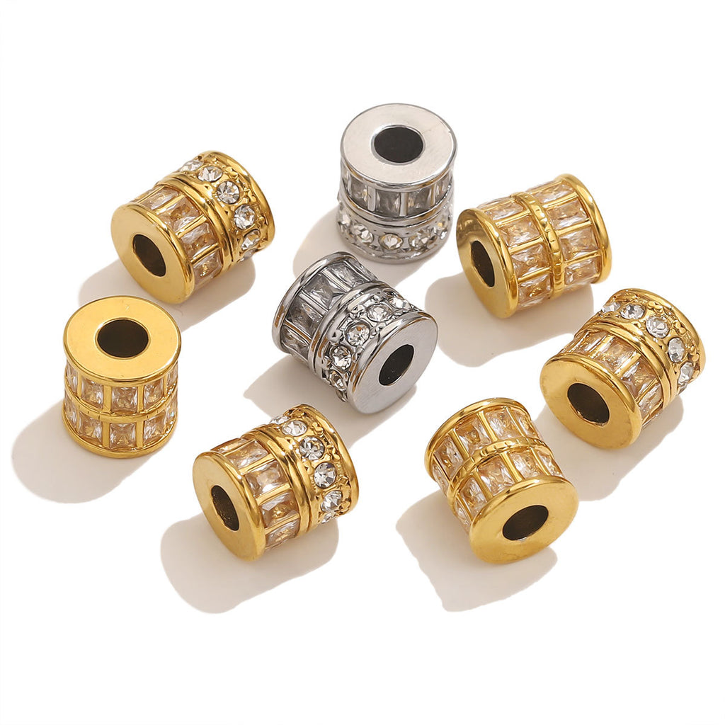 Seven cylindrical bead charms with clear crystal-like rhinestones, shown in both gold and silver metal finishes on a white background.