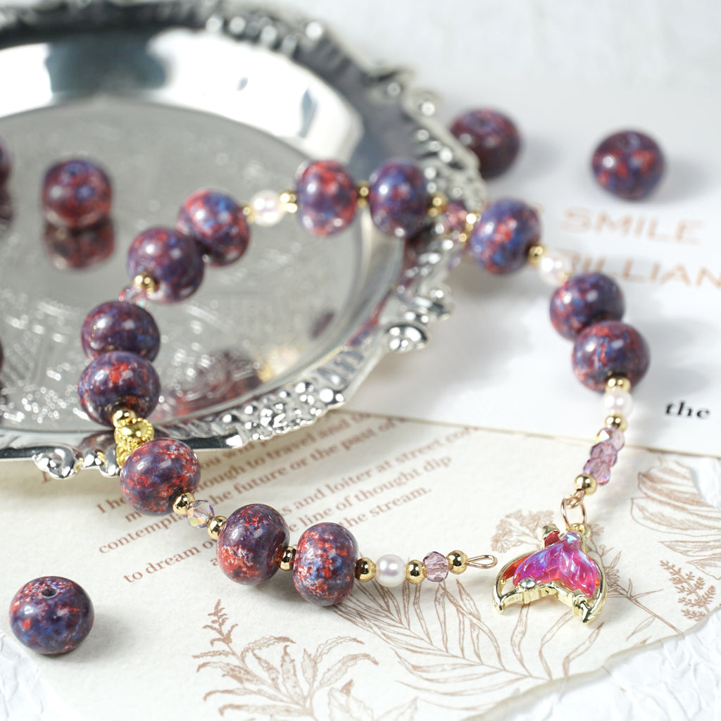 Beaded bracelet with purple and red marbled beads, gold links, and a pink butterfly charm