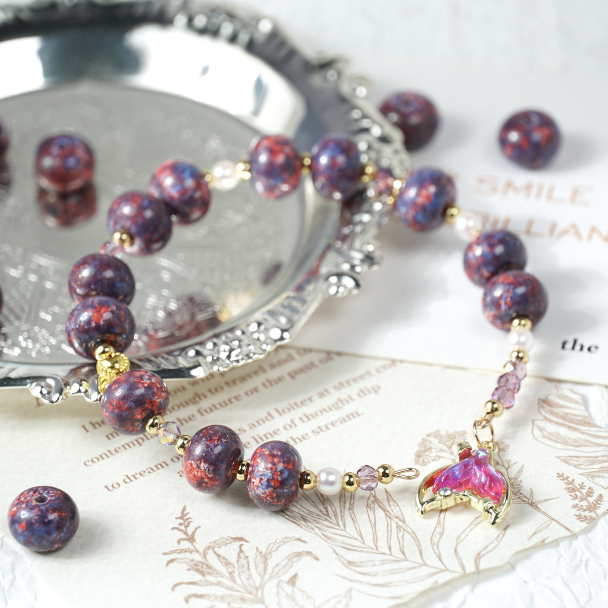 Beaded bracelet with purple and red marbled beads, gold links, and a pink butterfly charm