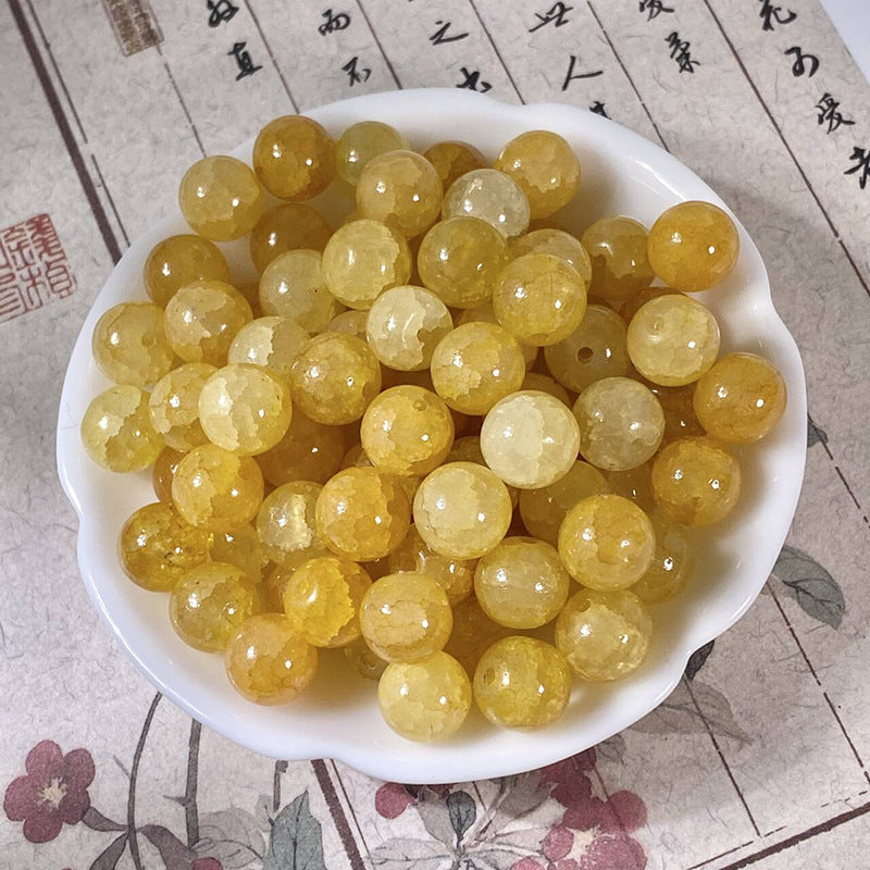 White ceramic dish filled with round polished yellow crackle beads