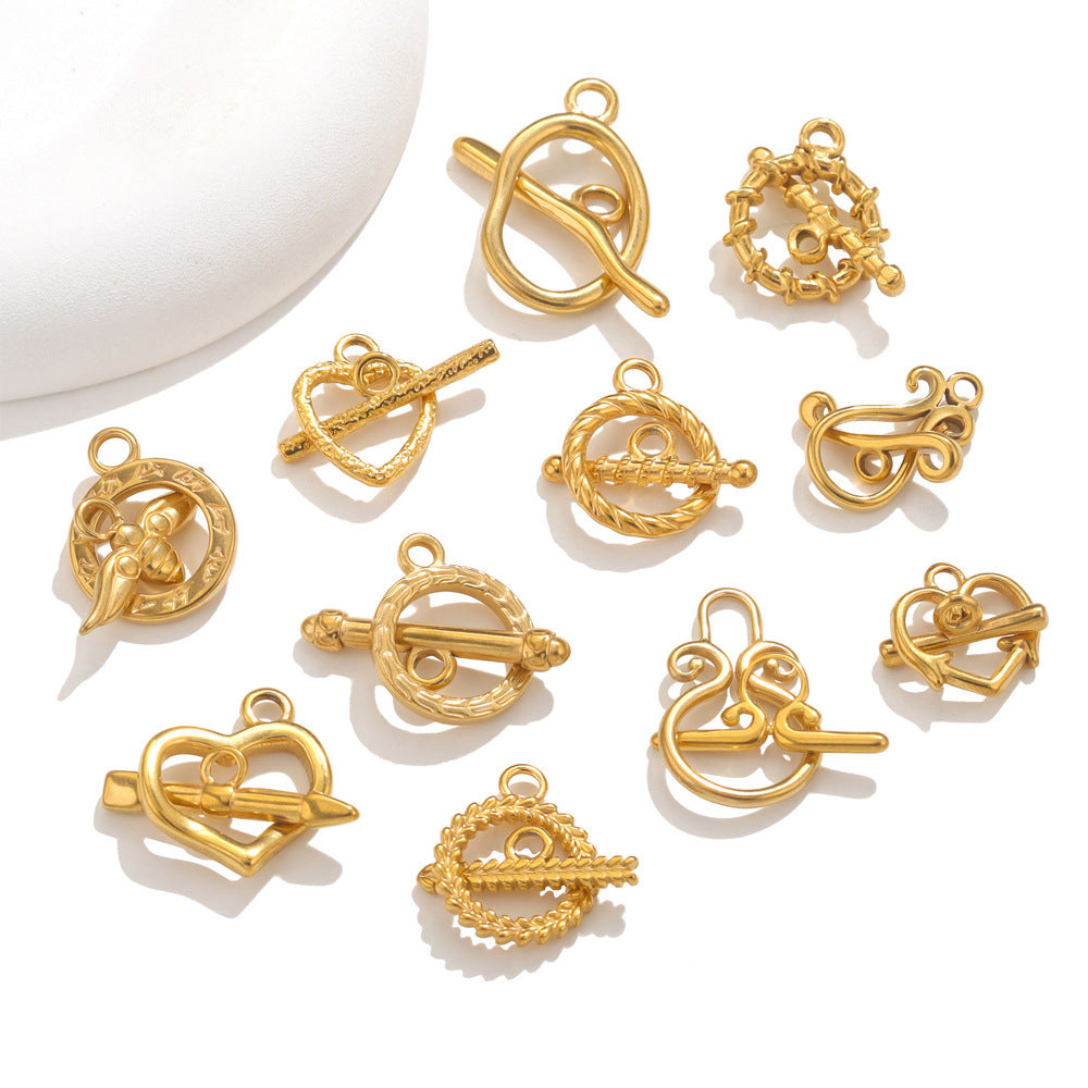 Ten gold-plated toggle clasp charms in assorted designs on white background with ceramic dish edge