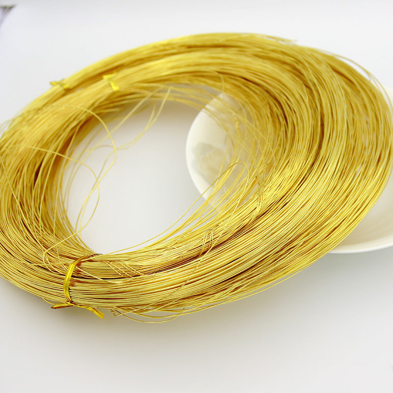 A coiled bundle of thin yellow-gold wire or cord, photographed on a plain white background with a white plate partially visible underneath.