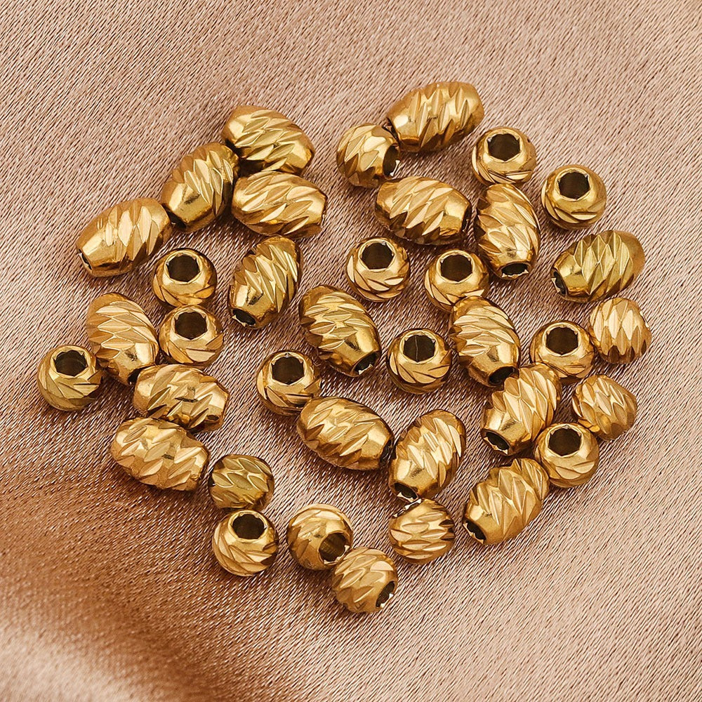 Gold-plated diamond-cut stainless steel wheel spacer beads with textured edges on beige fabric