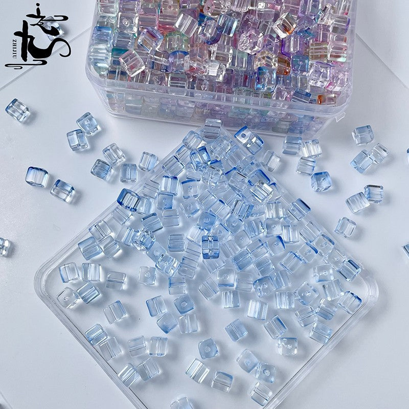 Clear cube glass beads with blue edges scattered on white, storage box