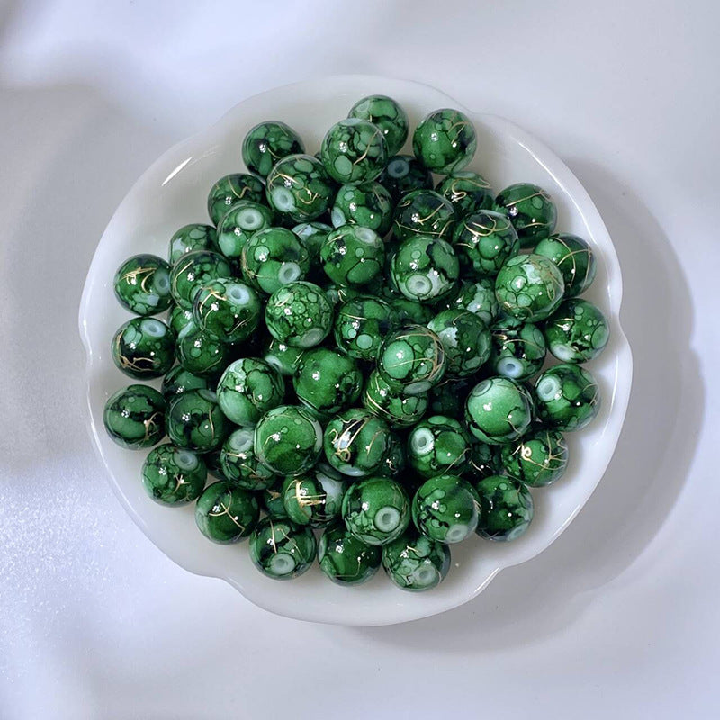 White bowl of marbled green glass beads with gold-silk veining