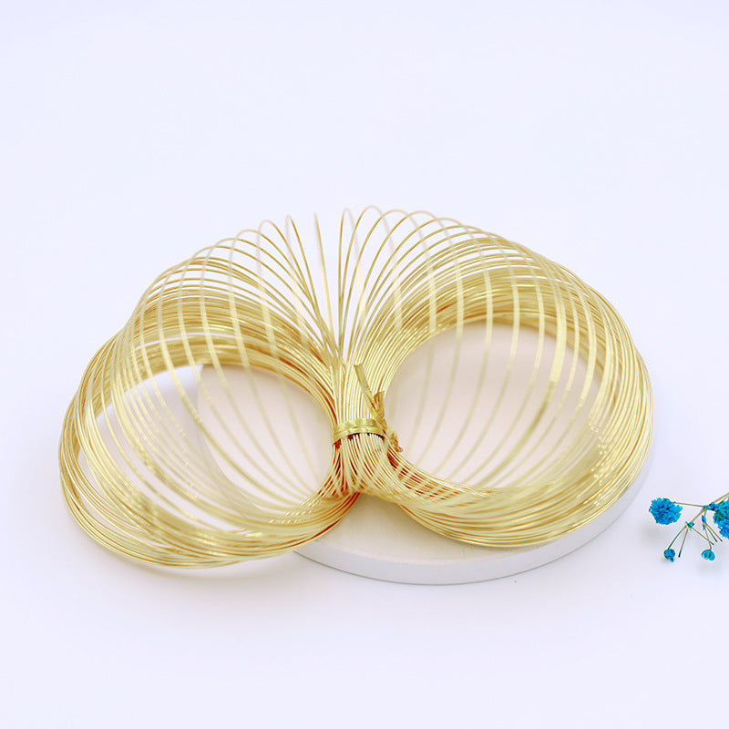 Gold-plated memory wire bundle tied in center and fanned out on white circular base with blue flowers