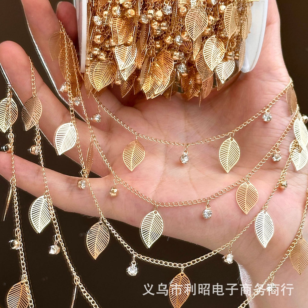 Hand holding long strand of gold leaf chain with clear rhinestone accents