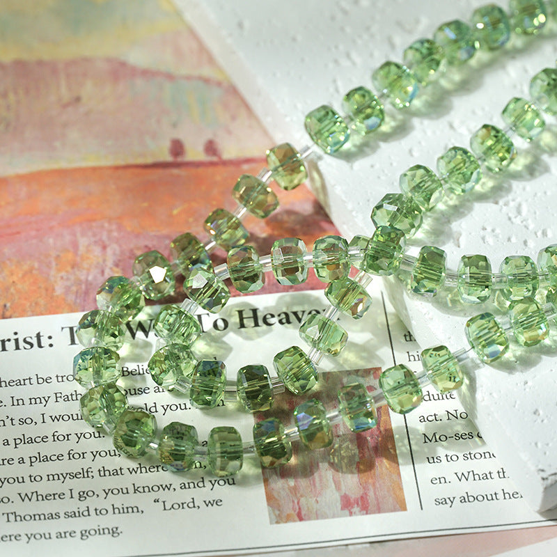 Faceted light green beads on a clear cord arranged diagonally across an open book with a textured white surface