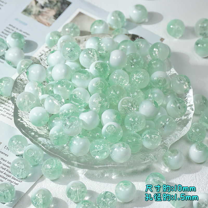 Mint green and white ice-crackle glass beads piled in a clear scalloped glass dish with scattered beads