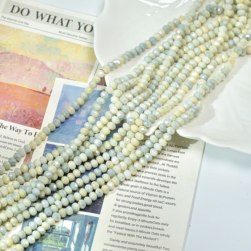 Strands of pale blue and white marbled faceted porcelain beads on open book