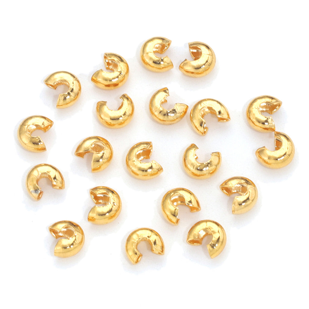 Small gold C-shaped crimp bead covers scattered on a white background.