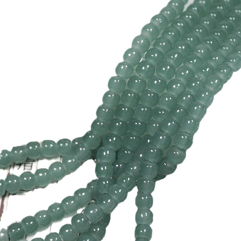 Green translucent round beads strung in multiple strands on a white background.