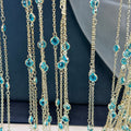 Gold-tone chain fringe necklace with faceted light blue gemstones on dark